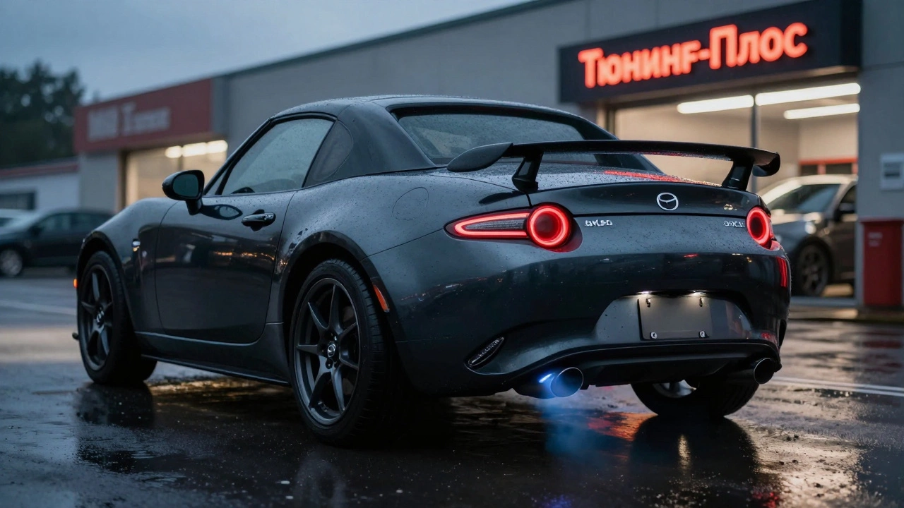 Mazda MX-5 на мокрой дороге при закате с видимым спортивным выхлопом и легкосплавными дисками.